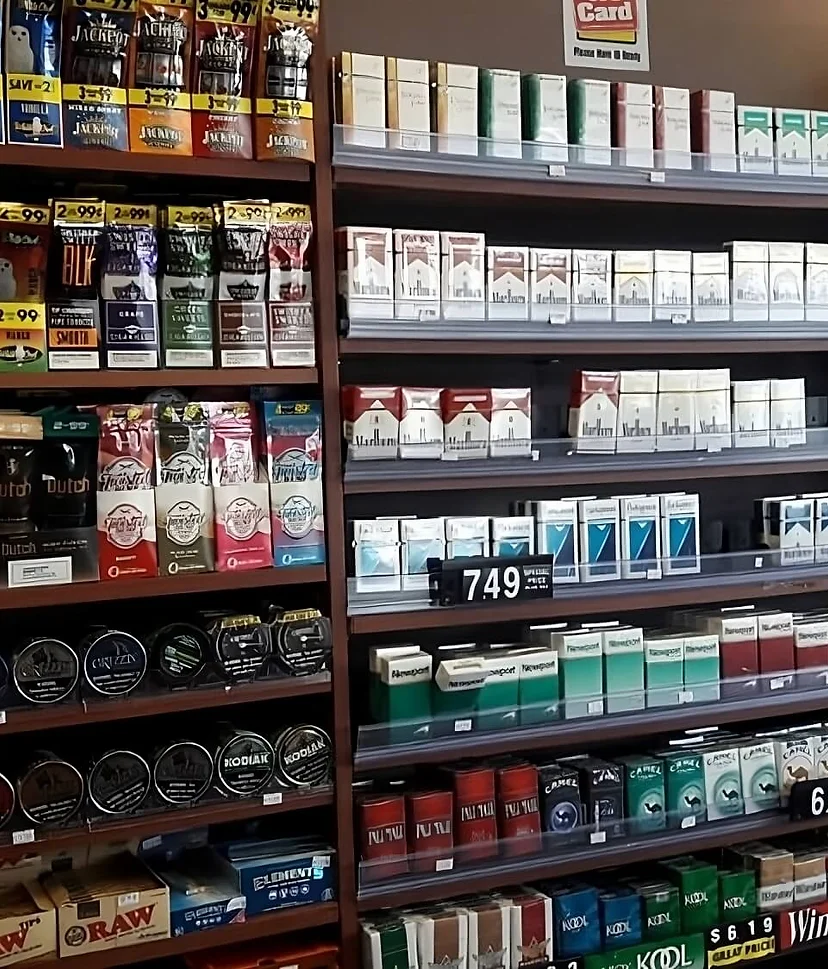 A man stands in front of a cigarette-filled store.